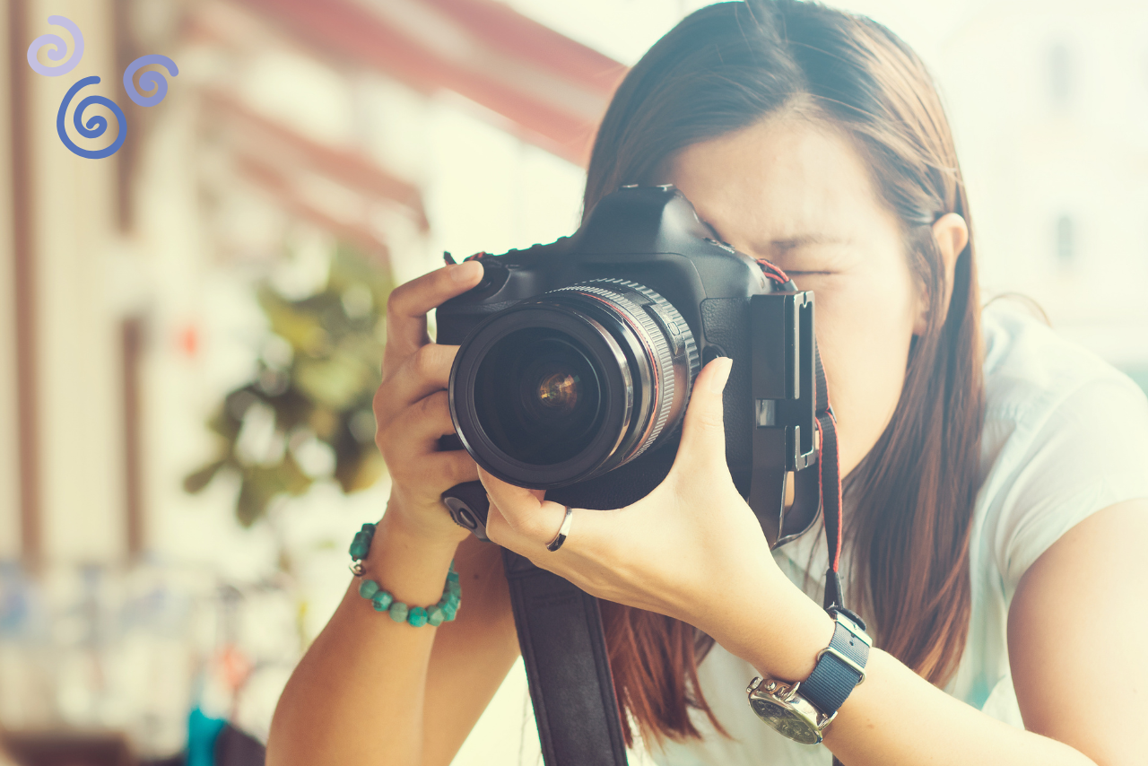 A girl aiming their camera to take a picture of something.