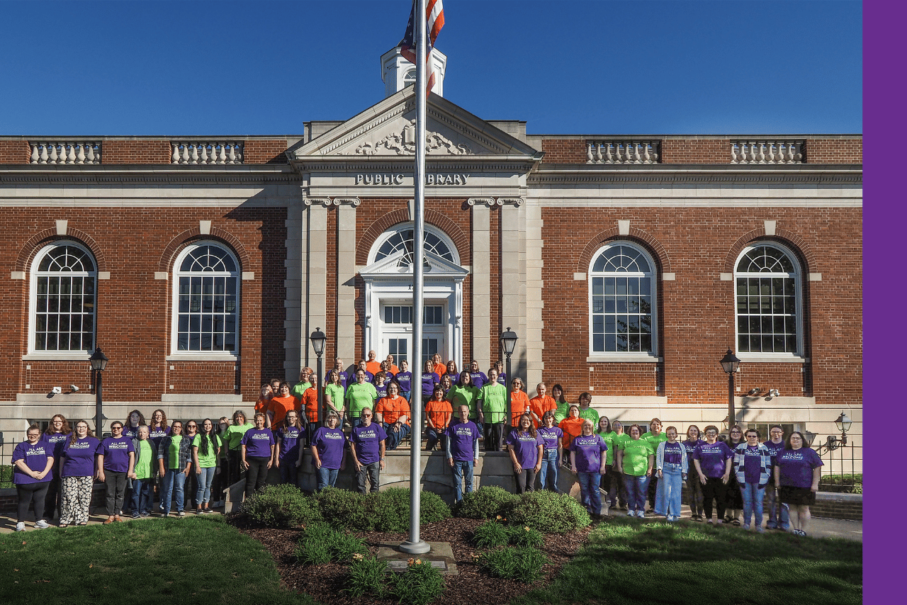 Library staff members pose in front of the historic Main library building.