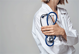 Side view of a female doctor holding a bunched up stethoscope to their right arm. 