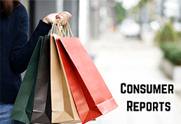 Arm holding a green, black, tan, and red shopping bags with the sidewalk blurred out in the background 