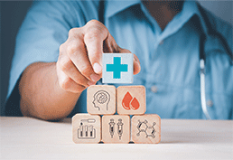 Doctor stacking building blocks with images of medical supplies.