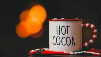 photo of a mug with Hot Cocoa written on it. The mug is sitting on a red and green coaster.