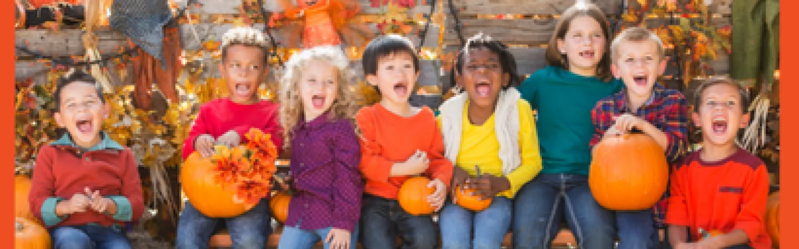 A group of kids smiling or shouting together as they sit on a hay bale.