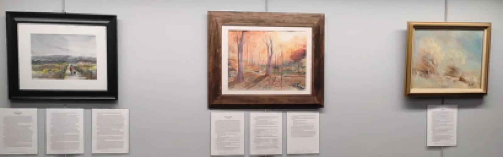 Three art pieces paired with written works in a hallway.