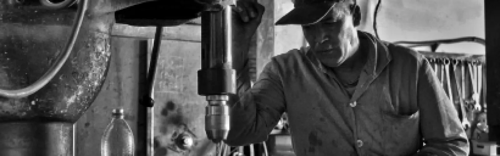 A black and white picture of a man operating a machine.