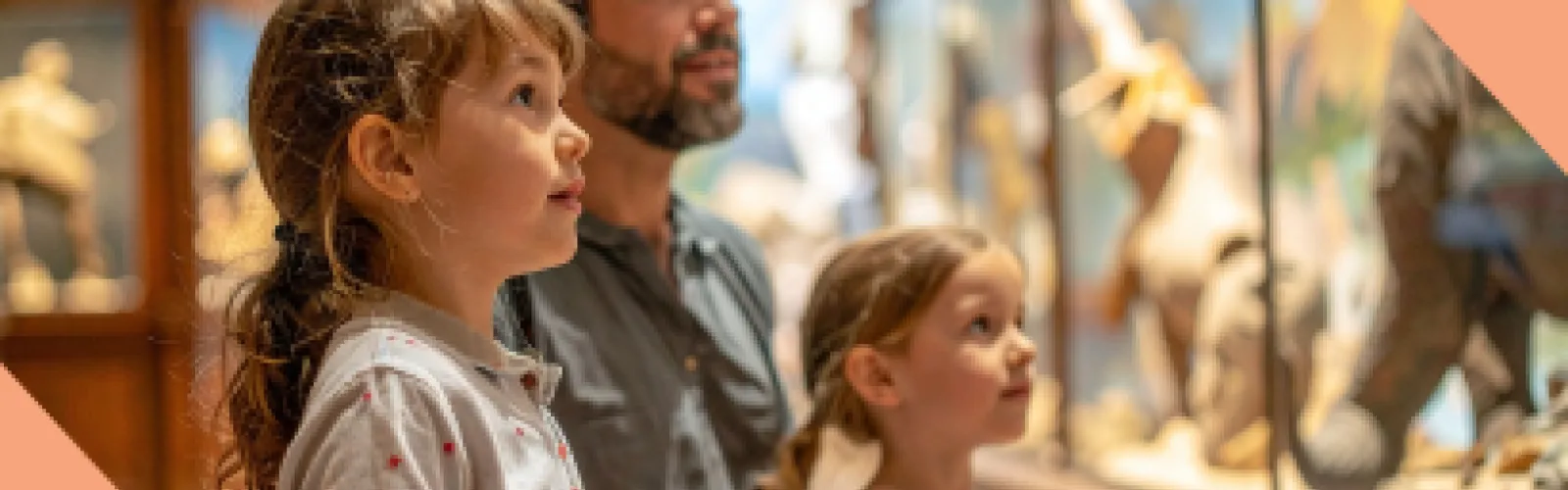 Two kids with their dad are looking at a glass display in a museum.