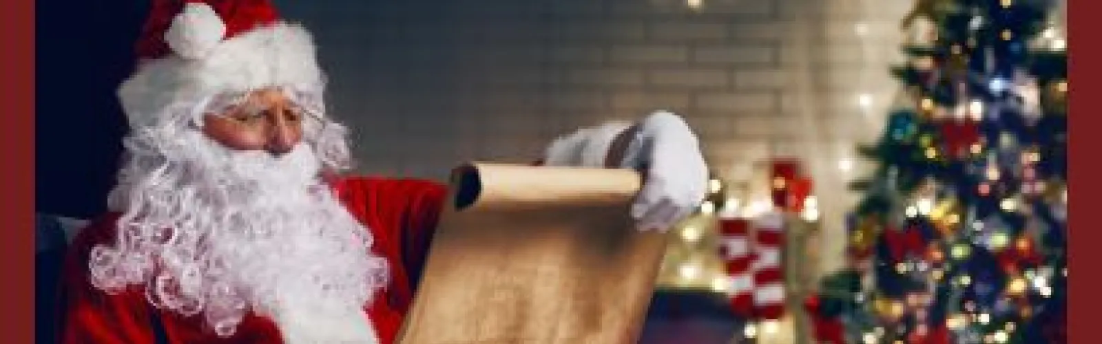 Santa looking at a list next to a Christmas tree.