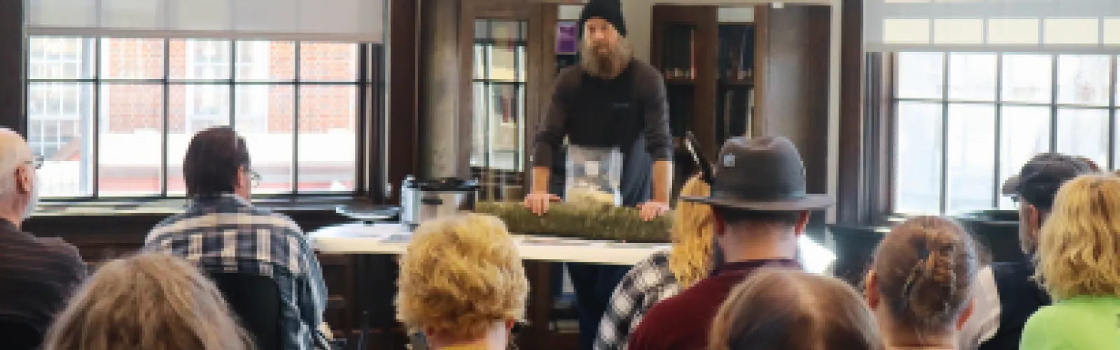 A speaker puts his hands on a log on a table as he speaks.
