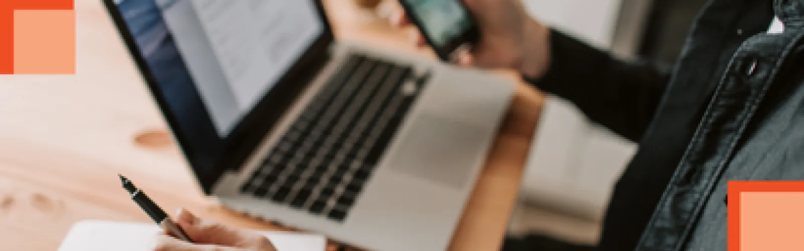 A person at their laptop with a phone in their hand. 