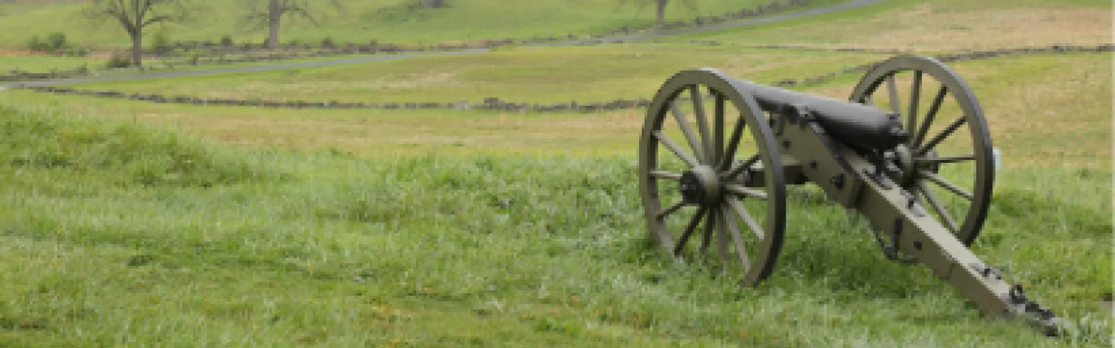 Vintage cannon sitting in an open field. 