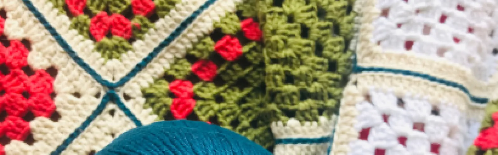 Close up of crocheted granny squares in white, red, and green. 