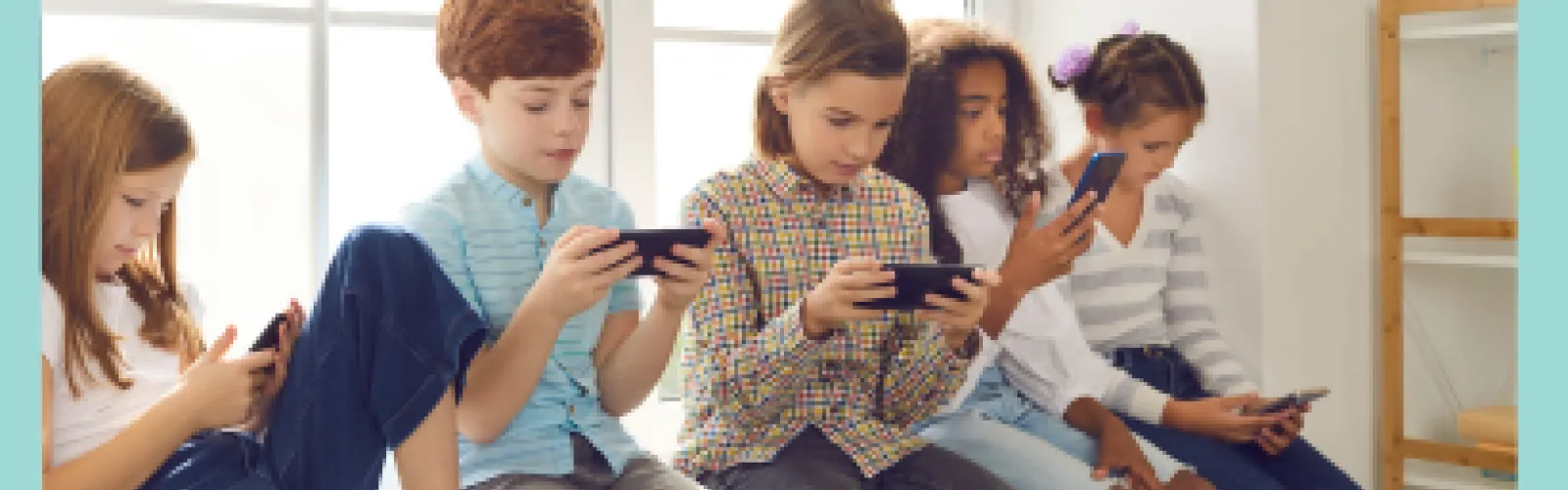 Five kids sitting on a window sill looking at their phones.