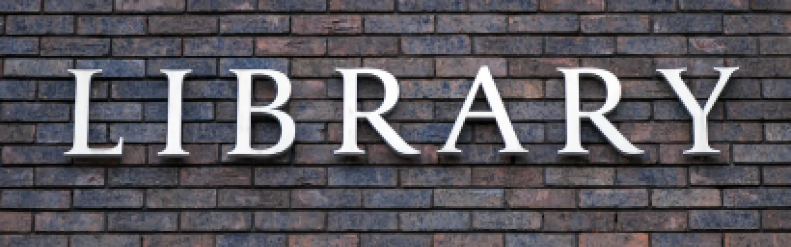 Brick wall with the words Library in metal lettering.
