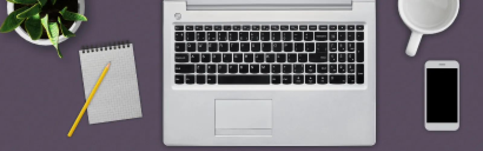 Close up of laptop keyboard with a coffee cup and cell phone to the right. A plant, notepad, and pencil sit to the left. 