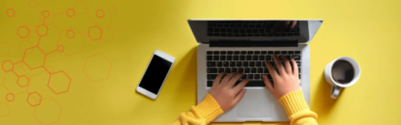Yellow background with hand sticking out of a yellow sweater typing on a laptop with a full coffee cup and cell phone next to it.